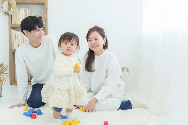 積み木を手にした子どもと、そばで見守る両親
